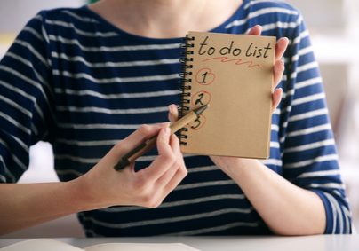 Close up of female hands writing to do list in spiral notepad